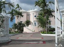 A palm tree lined driveway leading up to the pink and white Ocean West Boutique Hotel near Nassau Airport.
