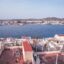 Houses on the waterfront, with hills in the background and blue skies above.