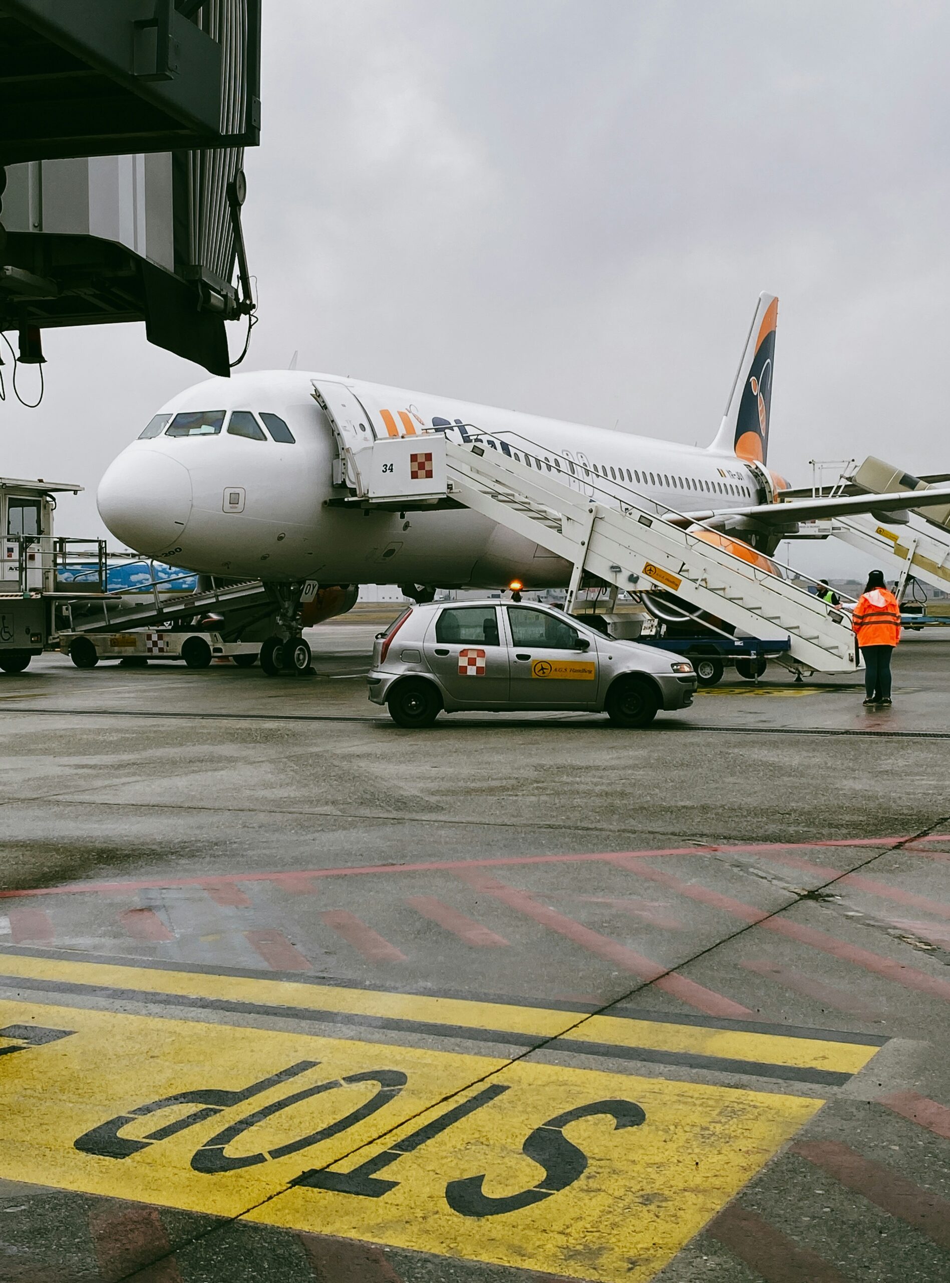 A vehicle and man in a high vis vest waiting on the tarmac next to a plane ready for passengers to disembark