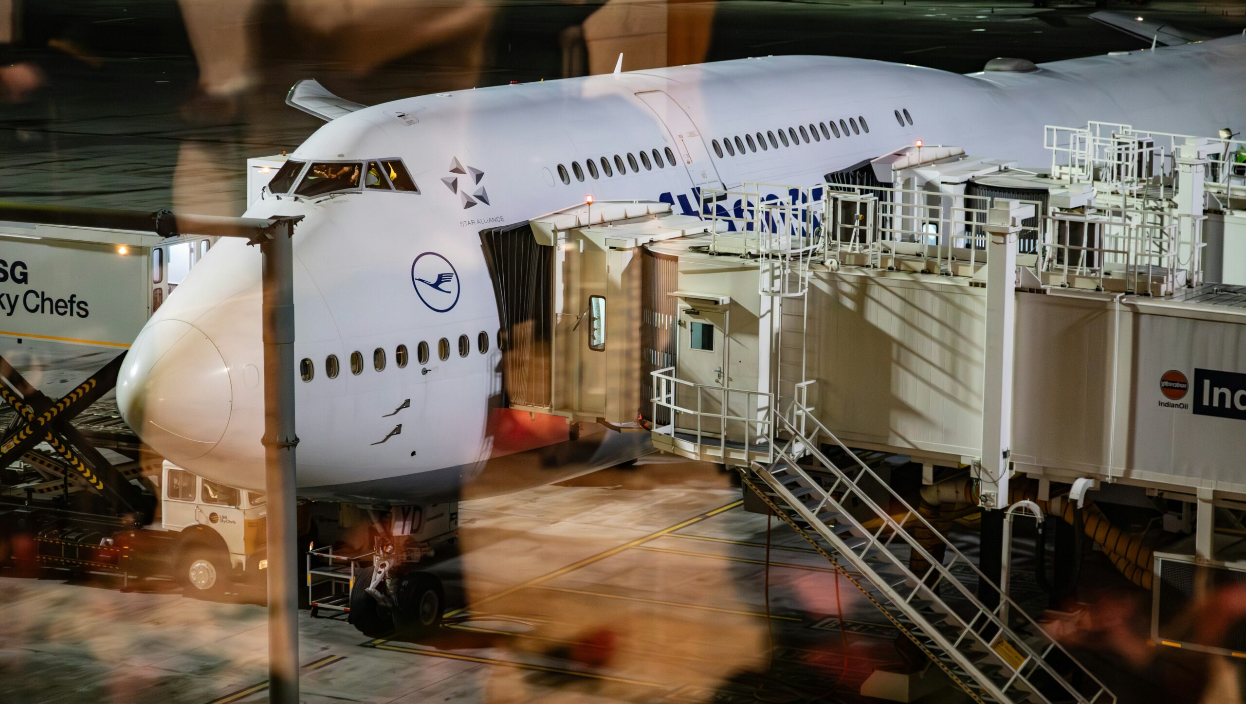 Aircraft stairs leading to a plane with its front door opened on the tarmac at night