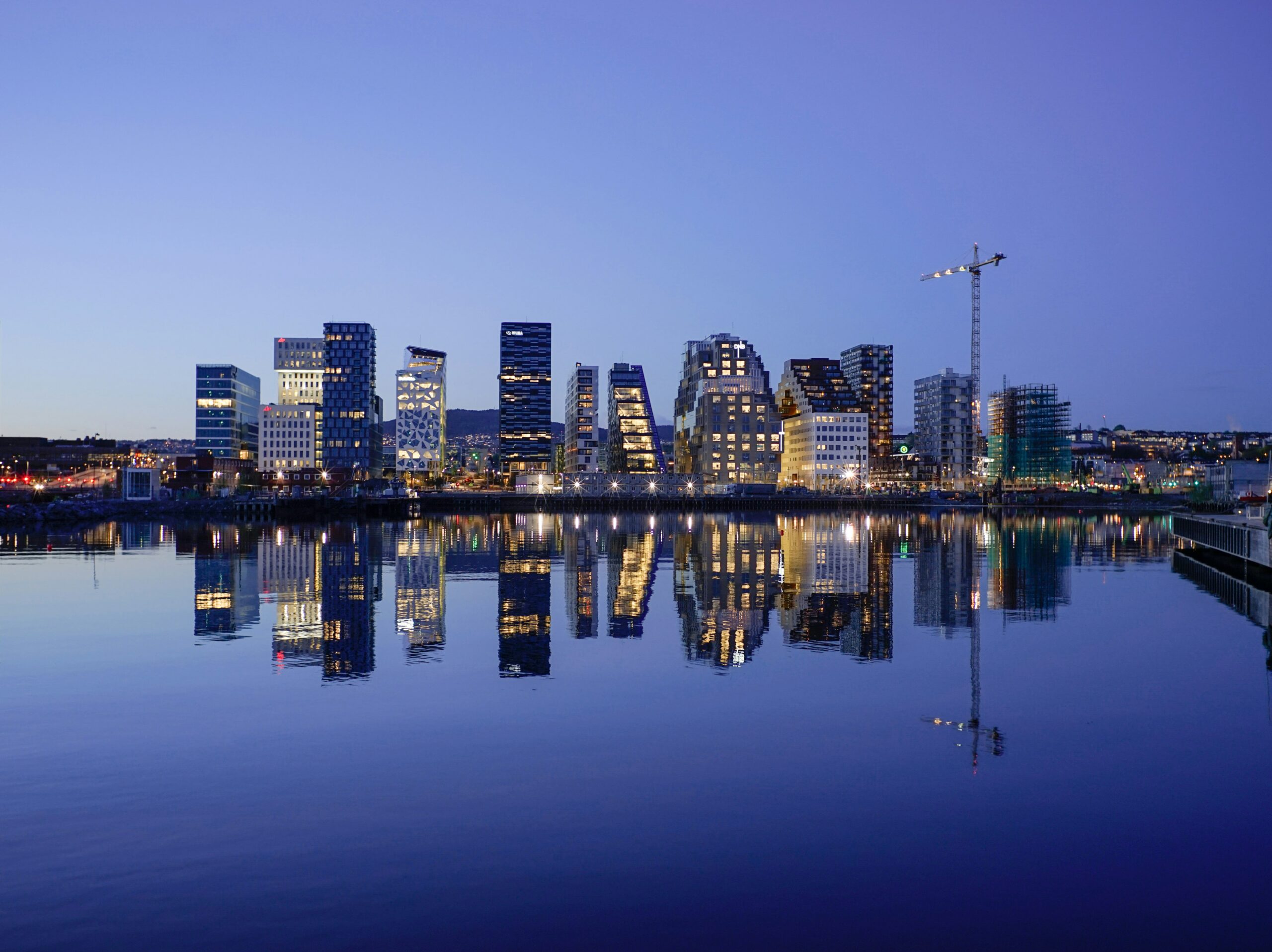A blue night sky and the city skyline of Oslo reflected on the water.