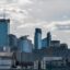 Skyline of Warsaw city center, with tall skyscrapers and a cloudy sky above.