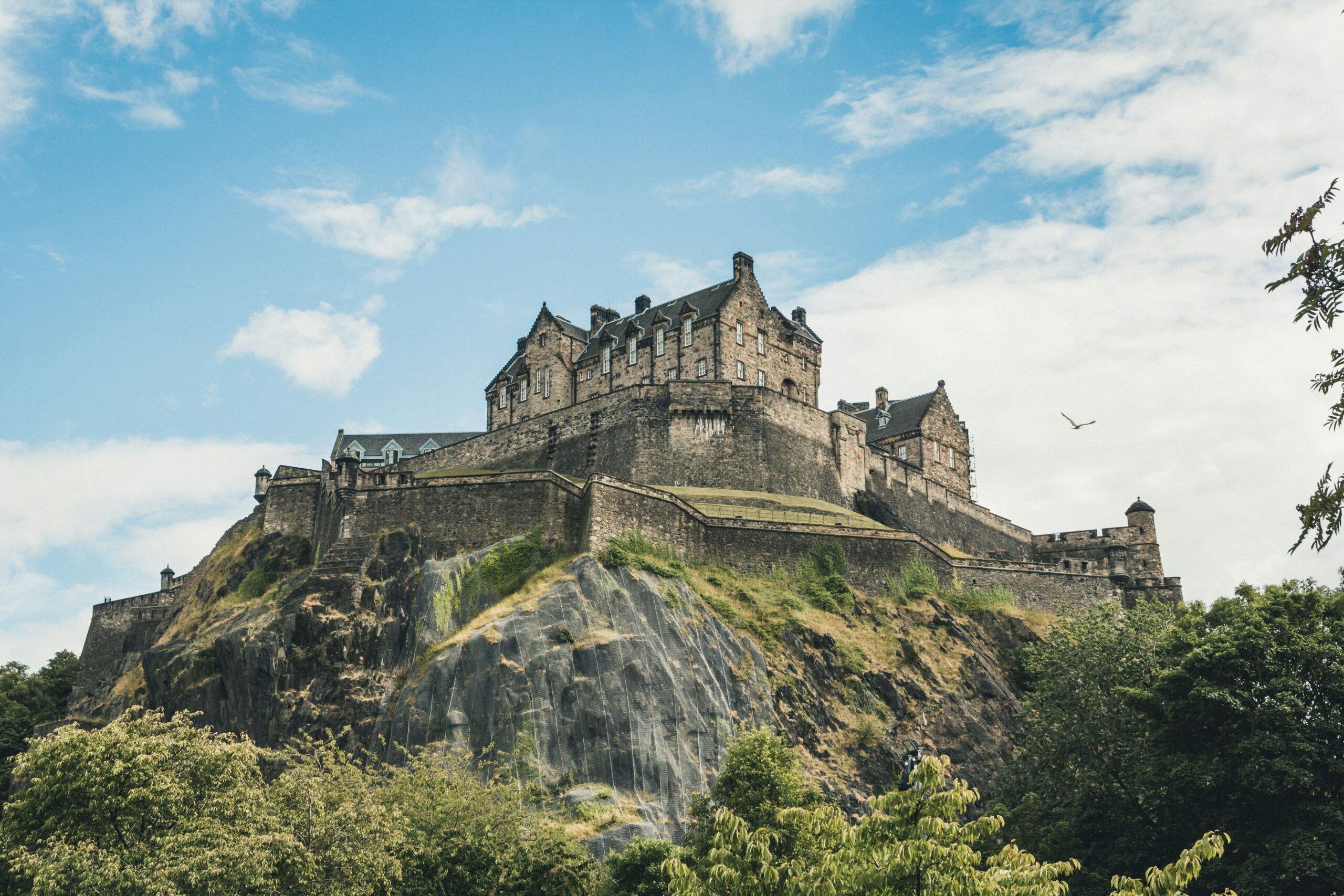 A large castle on top of a grassy hill in Edinburgh.