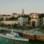 A boat sailing cruising past the shores of Belgrade city with lots of buildings and houses.