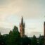 A view of two historic church towers above the skyline in Glasgow city surrounded by trees.
