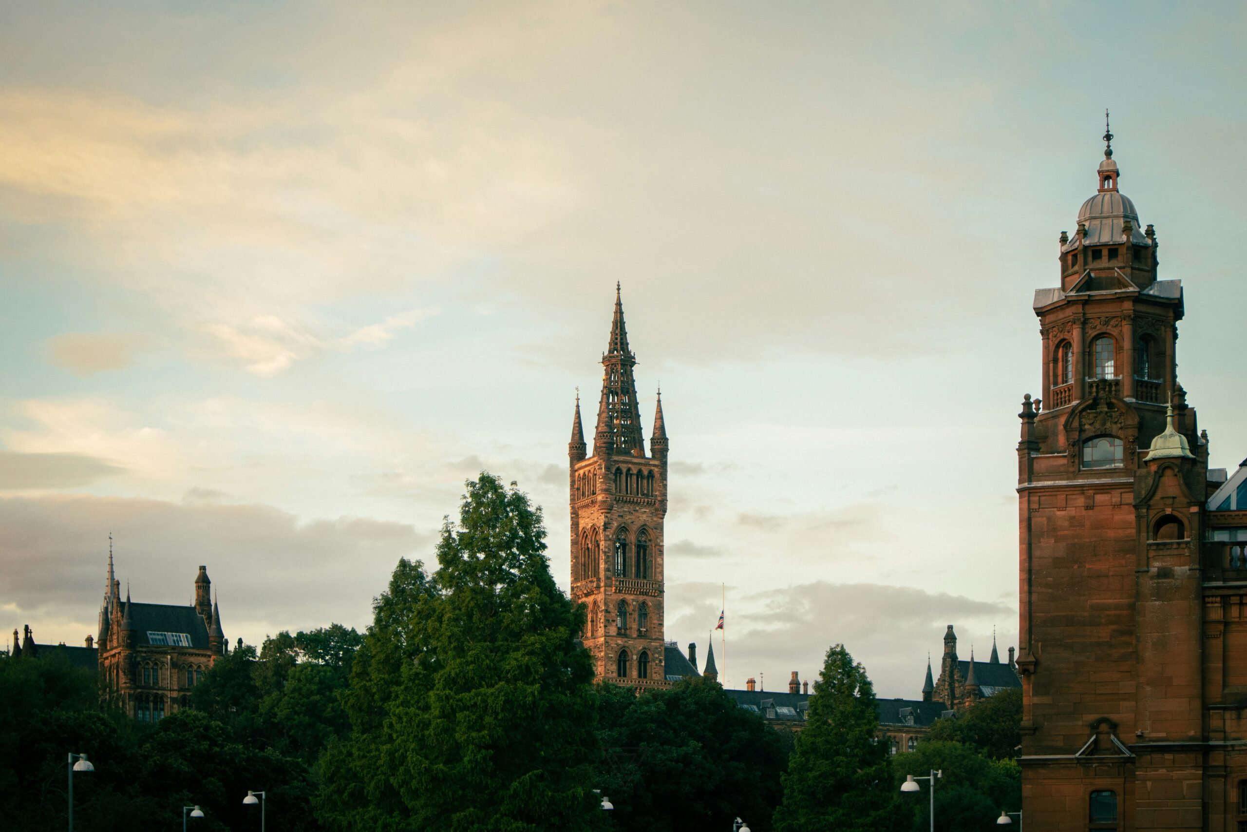 A view of two historic church towers above the skyline in Glasgow city surrounded by trees.