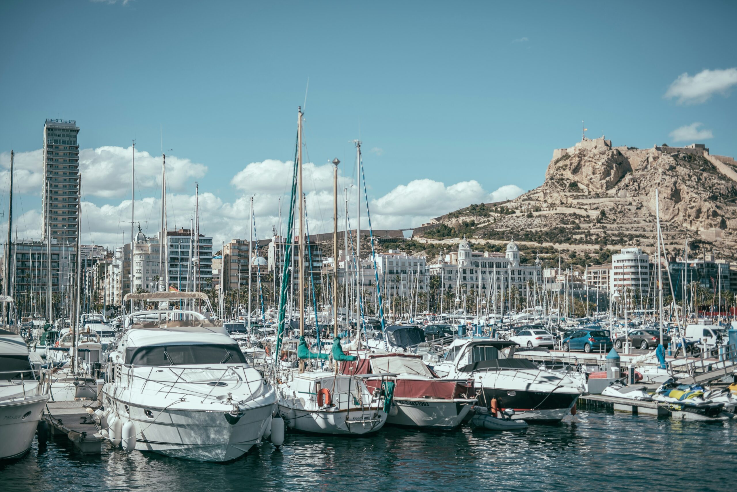 boats line the harbor in front of rocky hills
