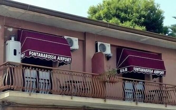 Two windows with maroon awnings at the Fontanarossa Airport B&B at Catania AIrport.