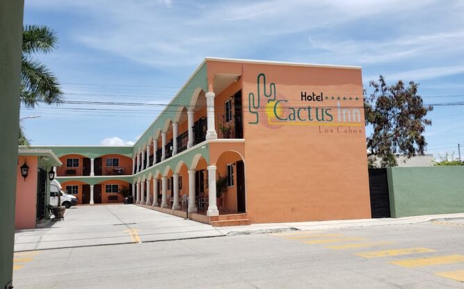 The Cactus Inn, a brown and green 'L' shaped hotel with a car park out the front.