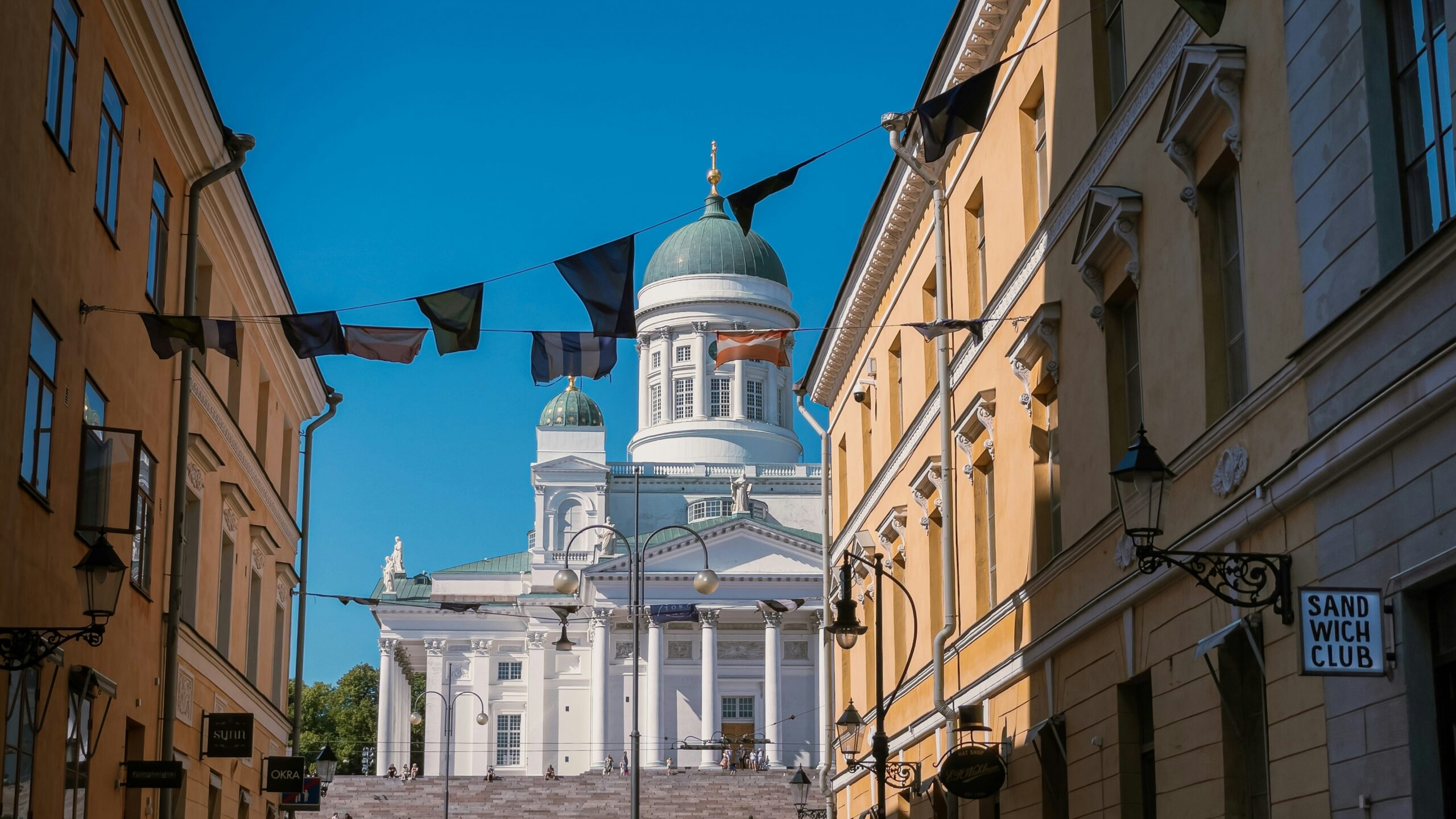 flags fly above a building under a blue sky