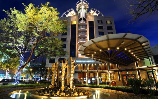 The entrance to the Intercontinental Hotel at Johannesburg Airport lit up at night with a tree placed in front.