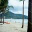 sandy beach with palm trees and mountains in the background in Phuket