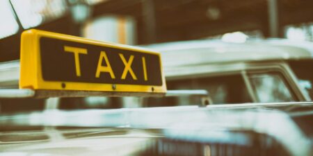 A yellow taxi sign on the roof of an airport taxi.