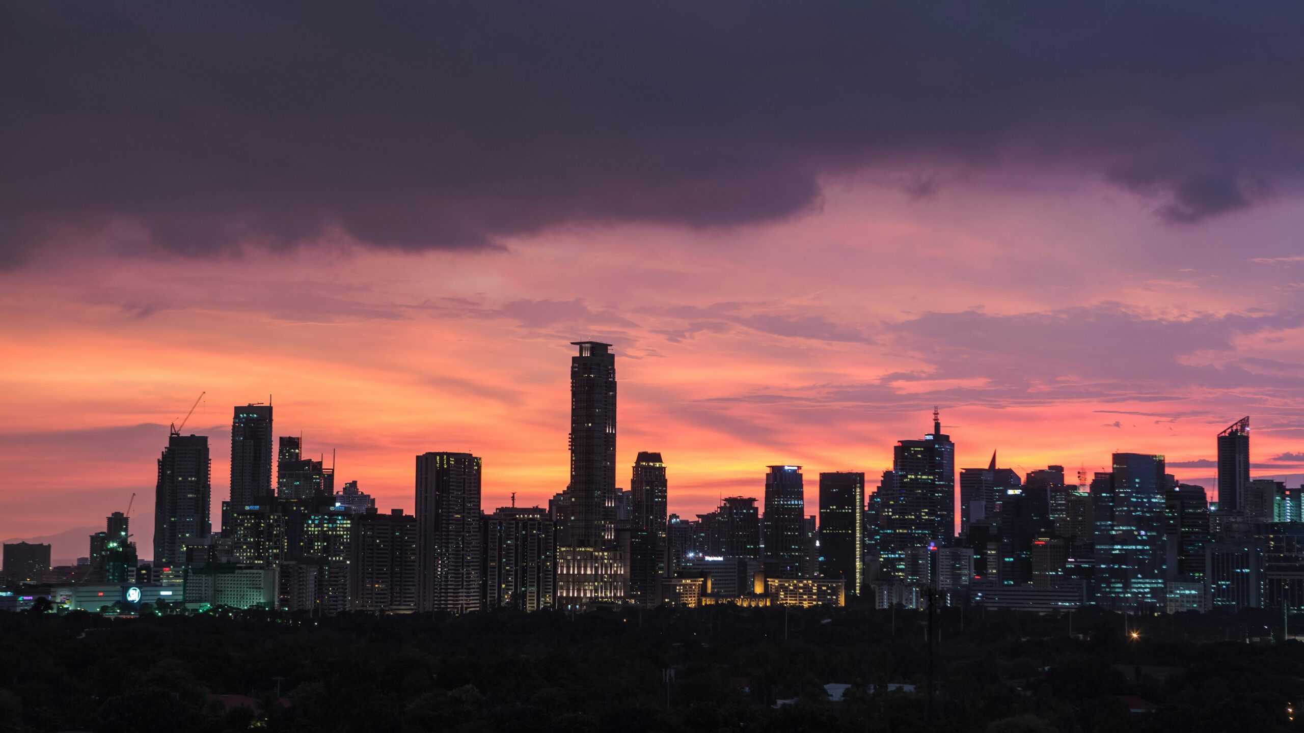 manila skyline silhouette under a dark pink orange and purple sunset sky
