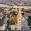 A birds eye view of central Budapest, with Matthias Church in the center and traditional buildings surrounding it., as well as a river running running through the center.