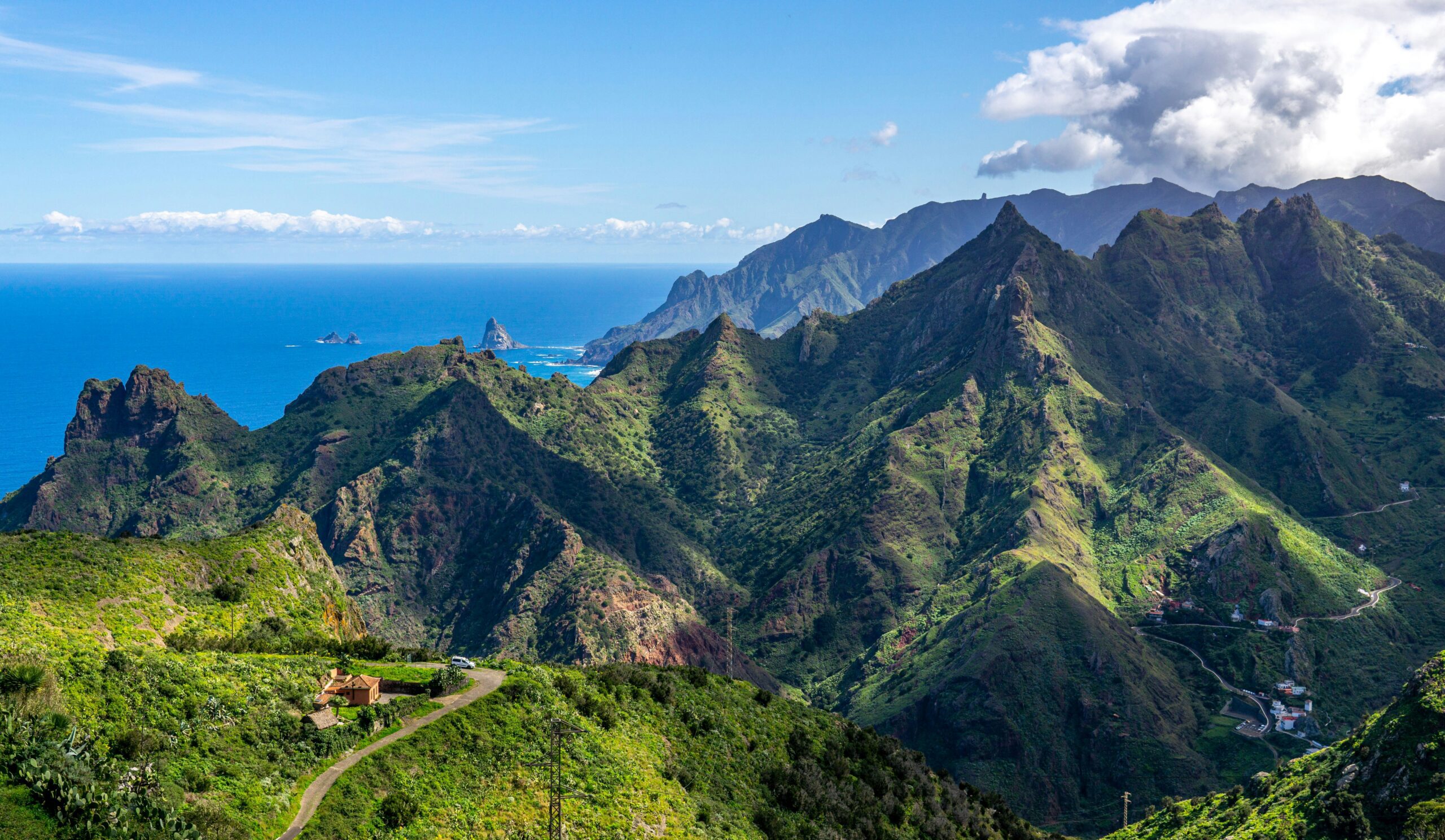 pointed mountains covered with greenery under a blue sky