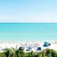 A beach with white sand, turquoise, palm trees and lots of people laying on the sand.