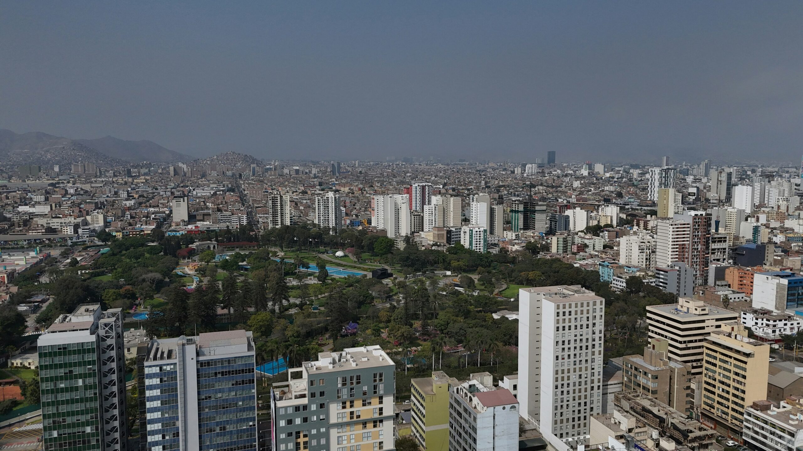 An aerial view of Lima City filled with sky-rise buildings and trees.