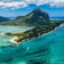 blue and green waters of Mauritius with a tall peak and jetty covered in greenery under a bright blue sky