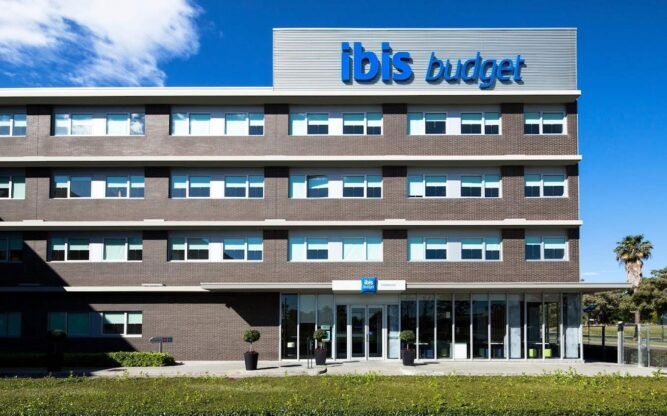 Front view of Ibis Budget Hotel near Barcelona Airport, with a blue Ibis sign on top of the building.