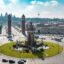 View of a grassy roundabout in central Barcelona, with cars on the road, and two towers bordering one of the exits.