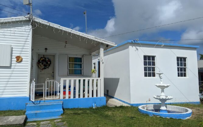 A quaint white cottage with a small fence on the island of Antigua