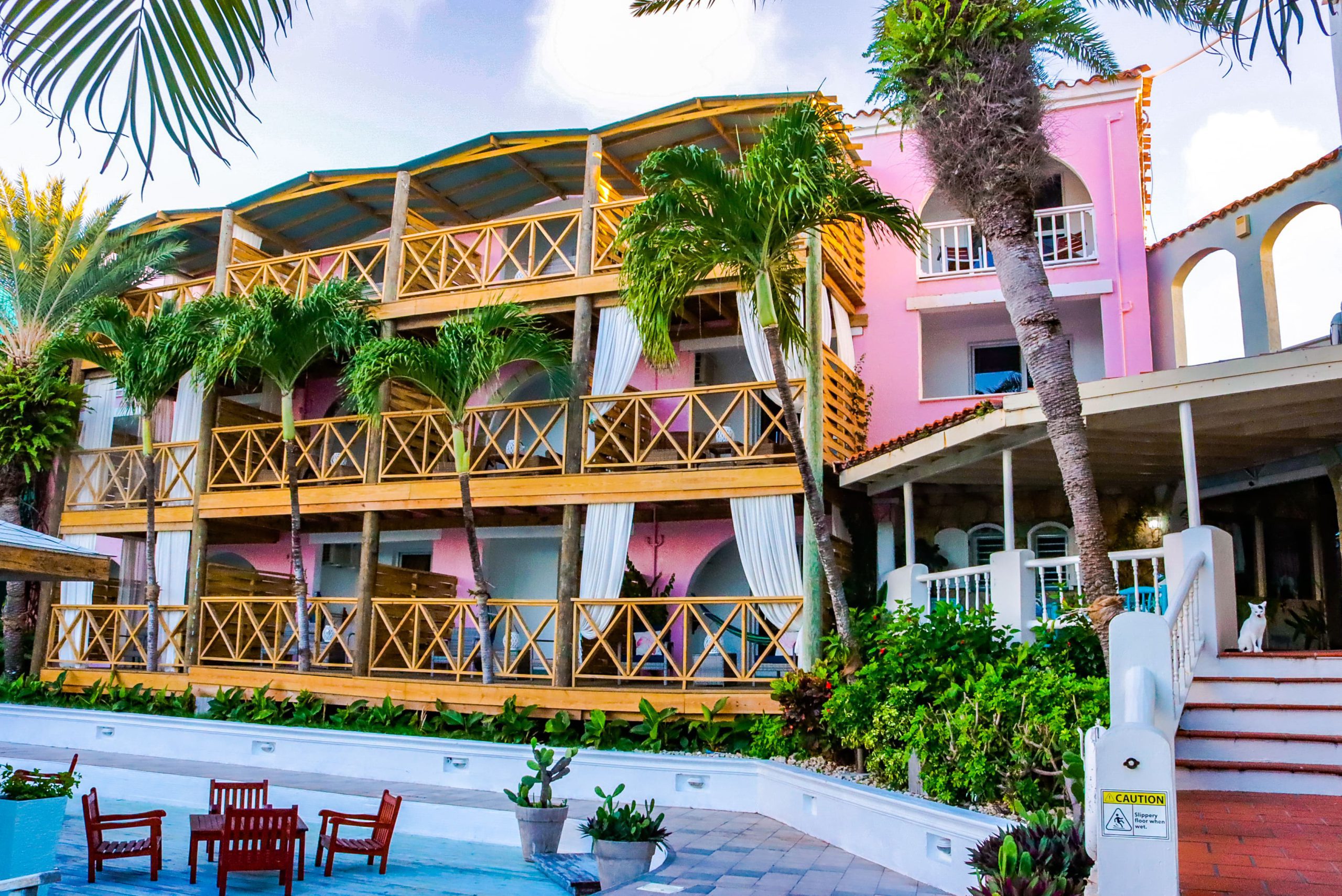 The pink facade and pool of Antigua's Ocean Point Resort and spa is framed by palm trees.