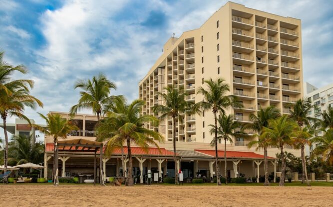 The Marriott Isla Verde Beach Resort near San Juan Airport with golden sand and palm trees in front.