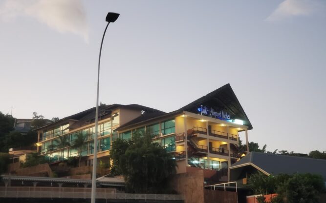 A view of the Tahiti Airport Motel against a setting sky with a lamp post in front.