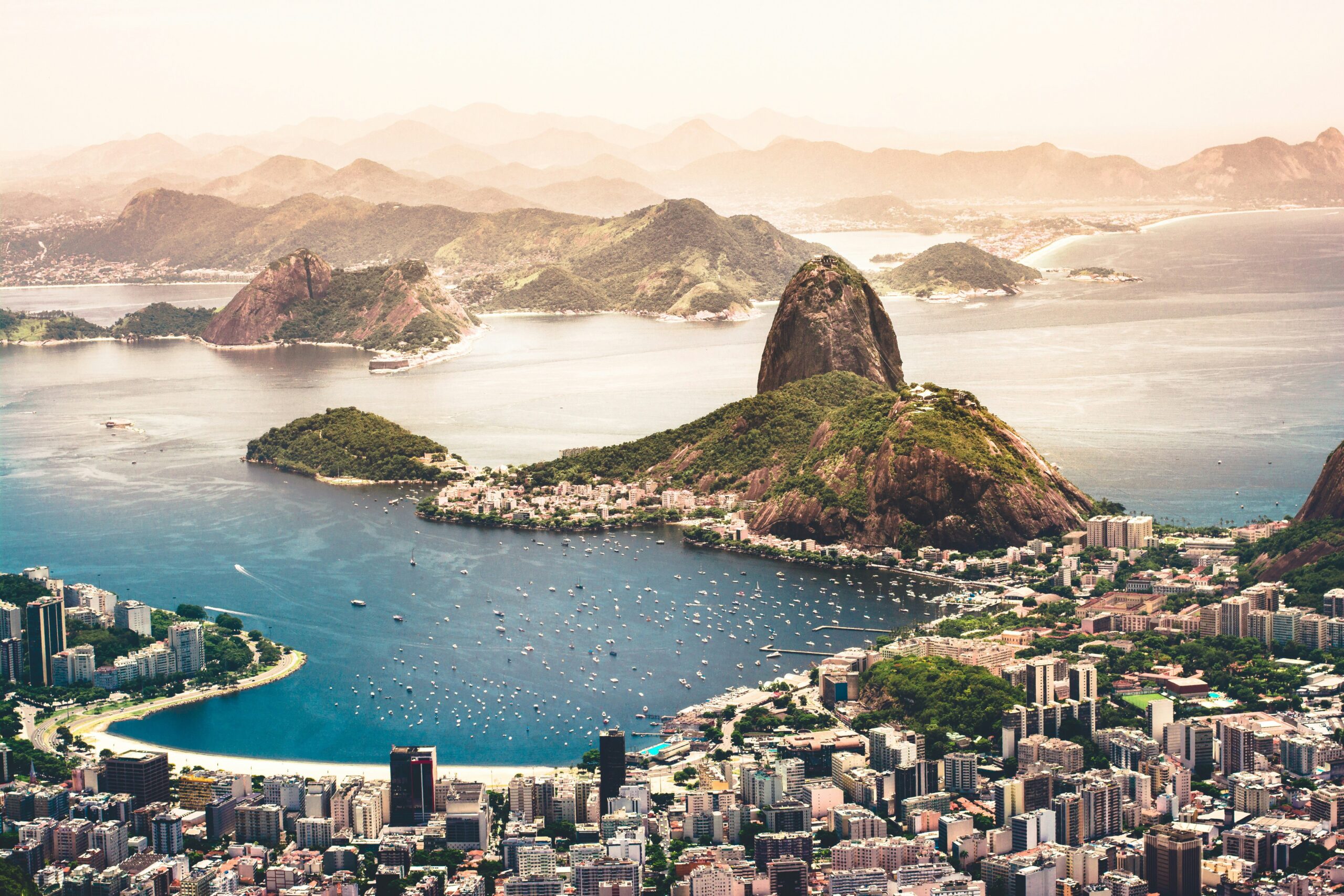 A city on the edge of the ocean with large pointed islands coming up out of the water with a setting sky in the background.