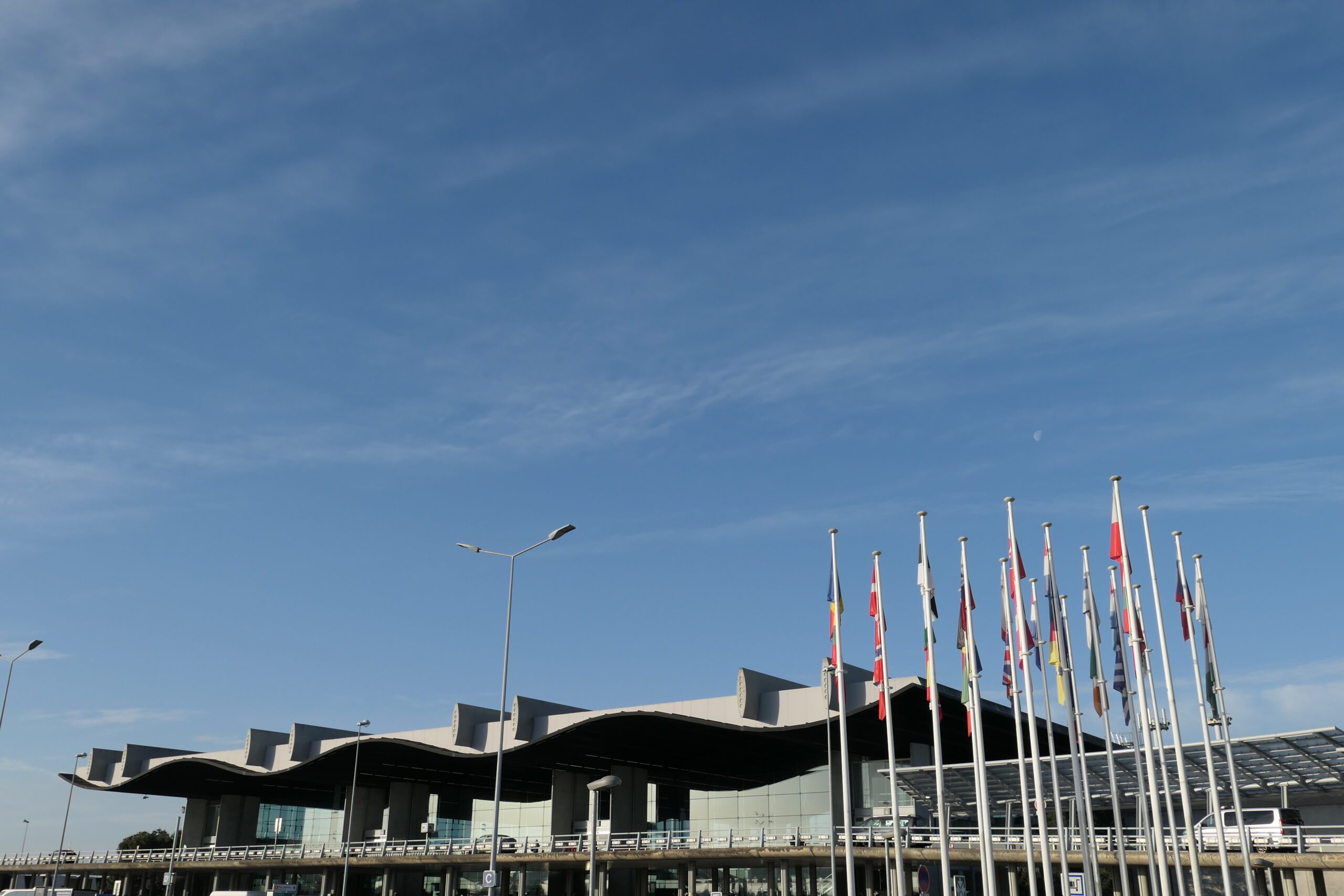 airport with numerous flags out front under a blue sky