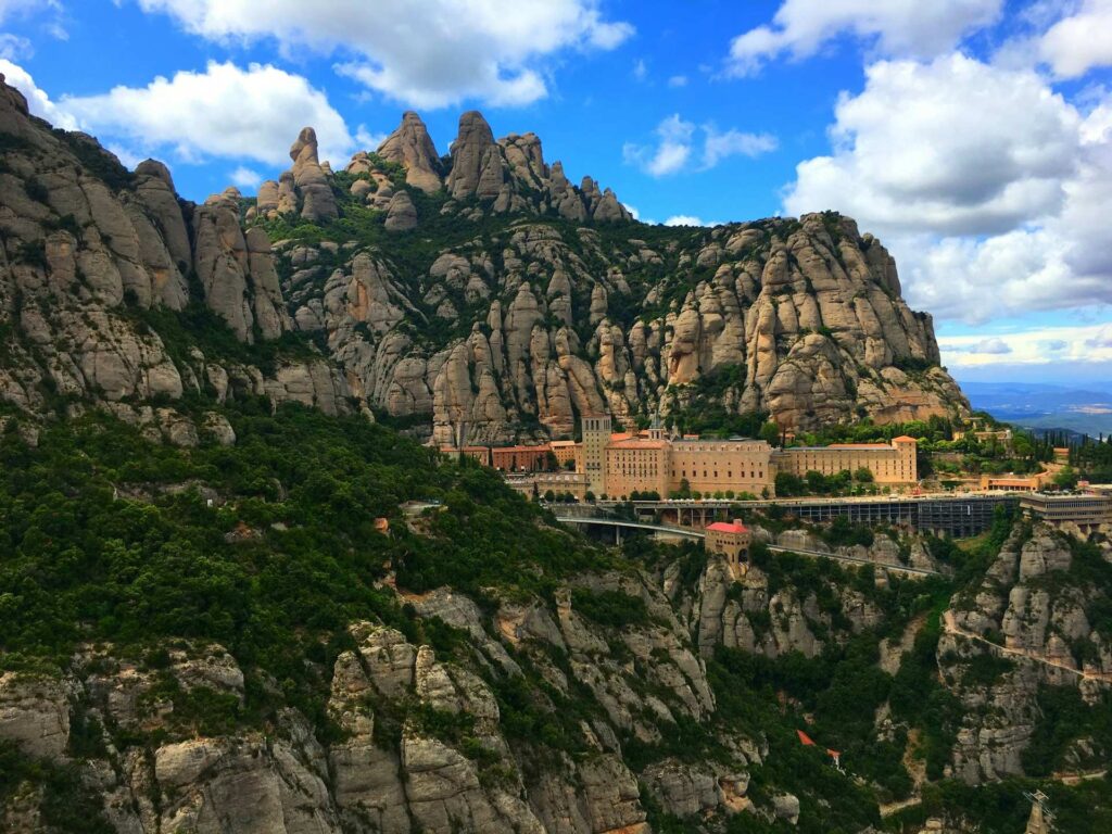 View of Montserrat with mountains behind and blue skies above.