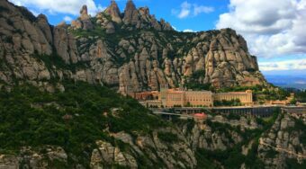 View of Montserrat with mountains behind and blue skies above.