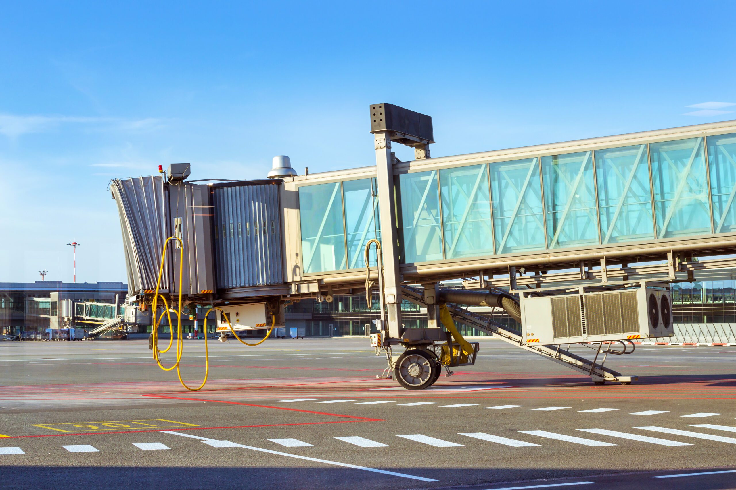a gate walkway attached to an airport hangs over the runway awaiting the next plane