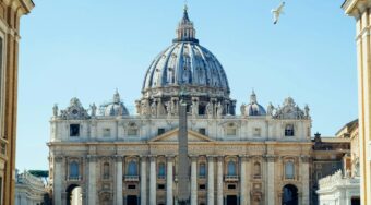 Front view of St Peter's Basilica in the Vatican City, with blue skies above.