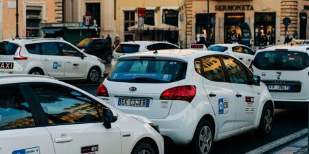 A queue of white Rome taxis on either side of a road in the city.