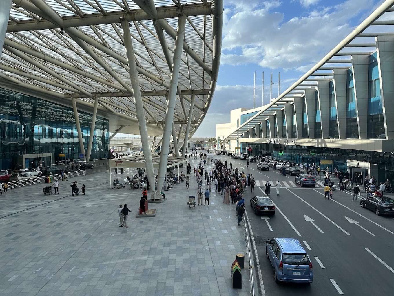 view along the sidewalk of Cairo Airport's beautiful outdoor pickup area lined with windows and a large overhang cover
