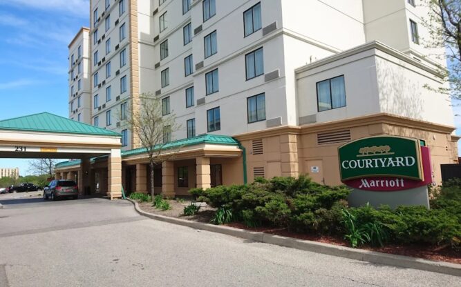 A sloped driveway leading up to the entrance of the white and yellow Courtyard Marriott Hotel near Toronto Airport.