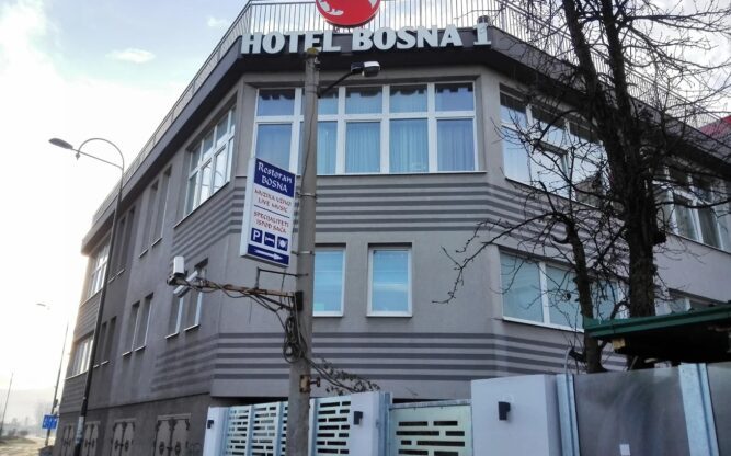 The grey concrete facade of the Hotel Bosna 1 with a red dragon sign on top of the building.