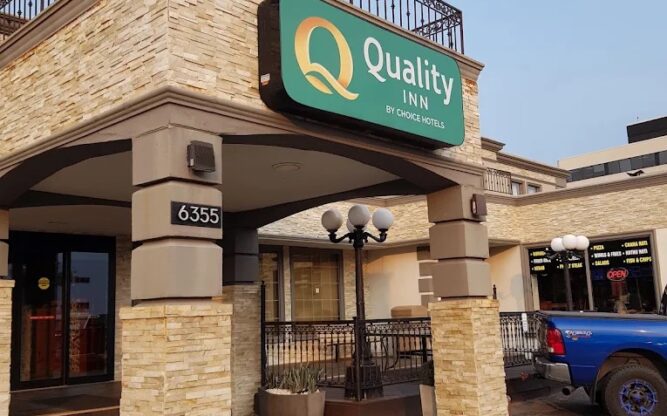 The entrance to the Quality Inn at Toronto Airport featuring a beige brick archway and a green sign.
