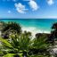 Panoramic view of Tulum’s rocky coastline and turquoise Caribbean Sea, featuring ancient Mayan ruins and lush greenery—highlighting the natural beauty awaiting travelers going to Tulum from Cancun Airport.