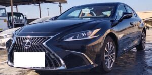 A sleek black Lexus sedan parked in a sunlit lot, commonly used as a premium taxi at. Dubai Airport