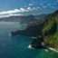 A green and luscious mountain meeting a vast and blue ocean.