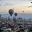 Dozens of hot air balloons floating above Cappadocia at sunrise.