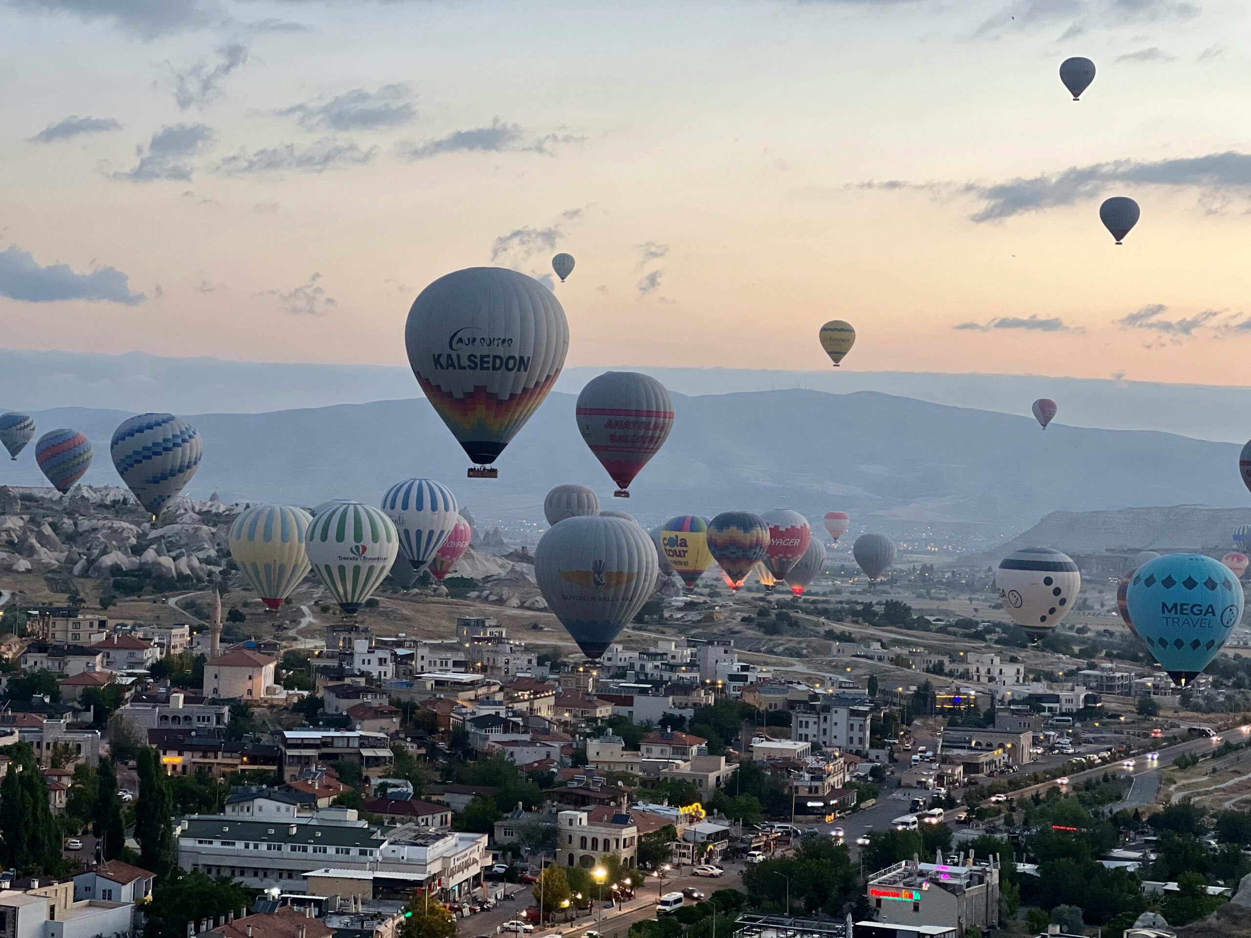 Dozens of hot air balloons floating above Cappadocia at sunrise.