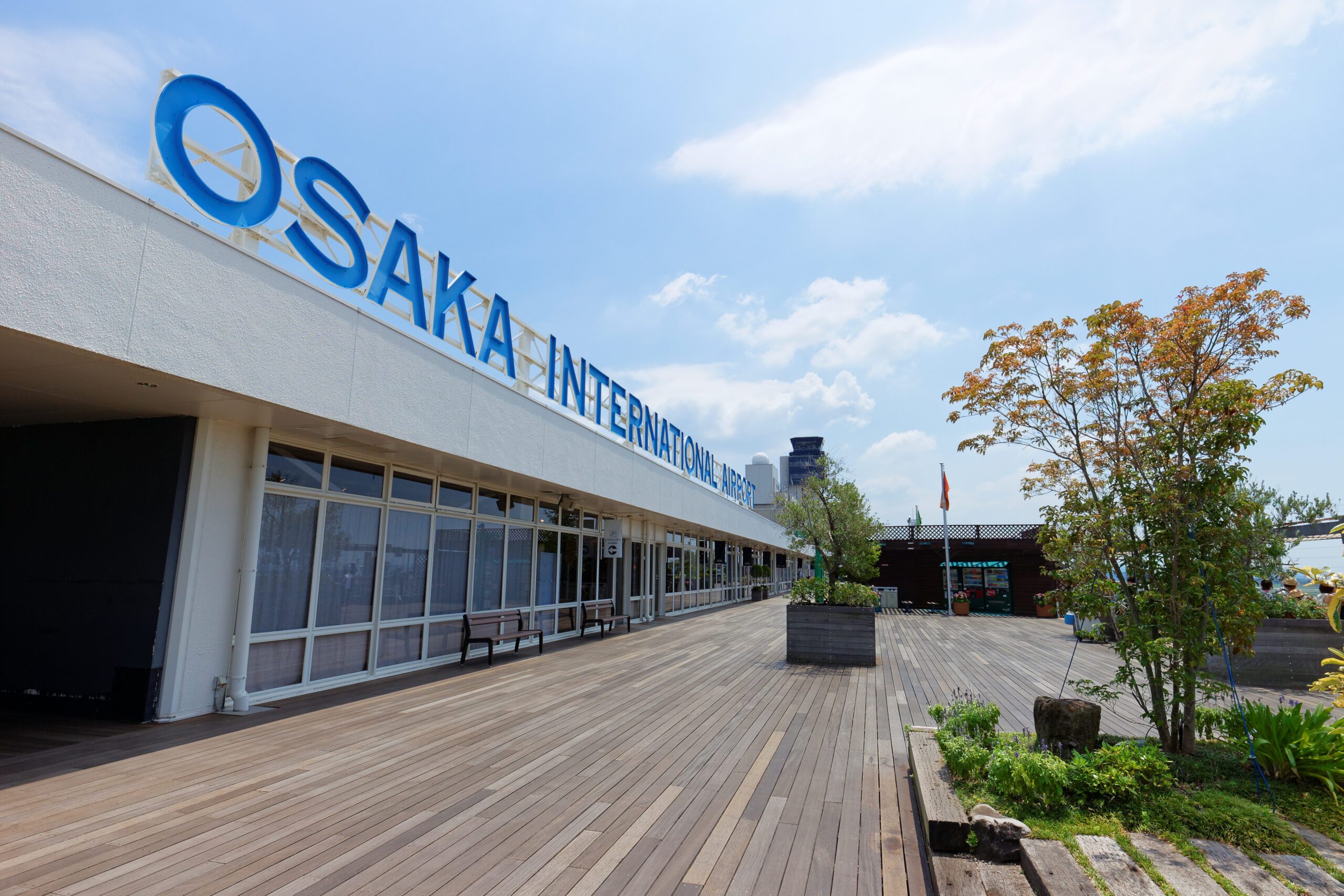 view outside the front of Osaka Airport with a blue letter sign on the top of the one-story building