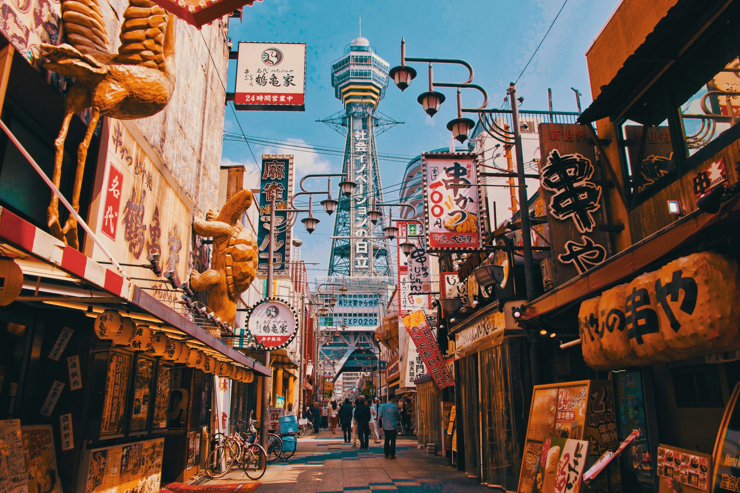a view down a city street in Osaka with many stores on either side and a tall tower in the background