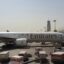 An Emirates plane parked outside an Al Maktoum DWC Airport terminal.