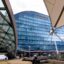 A huge glass building obstructed by part of a sail and a curved steel structure.