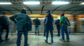 Commuters waiting on a metro platform in Athens as a train passes by, highlighting the convenience and affordability of budget transport in Athens.